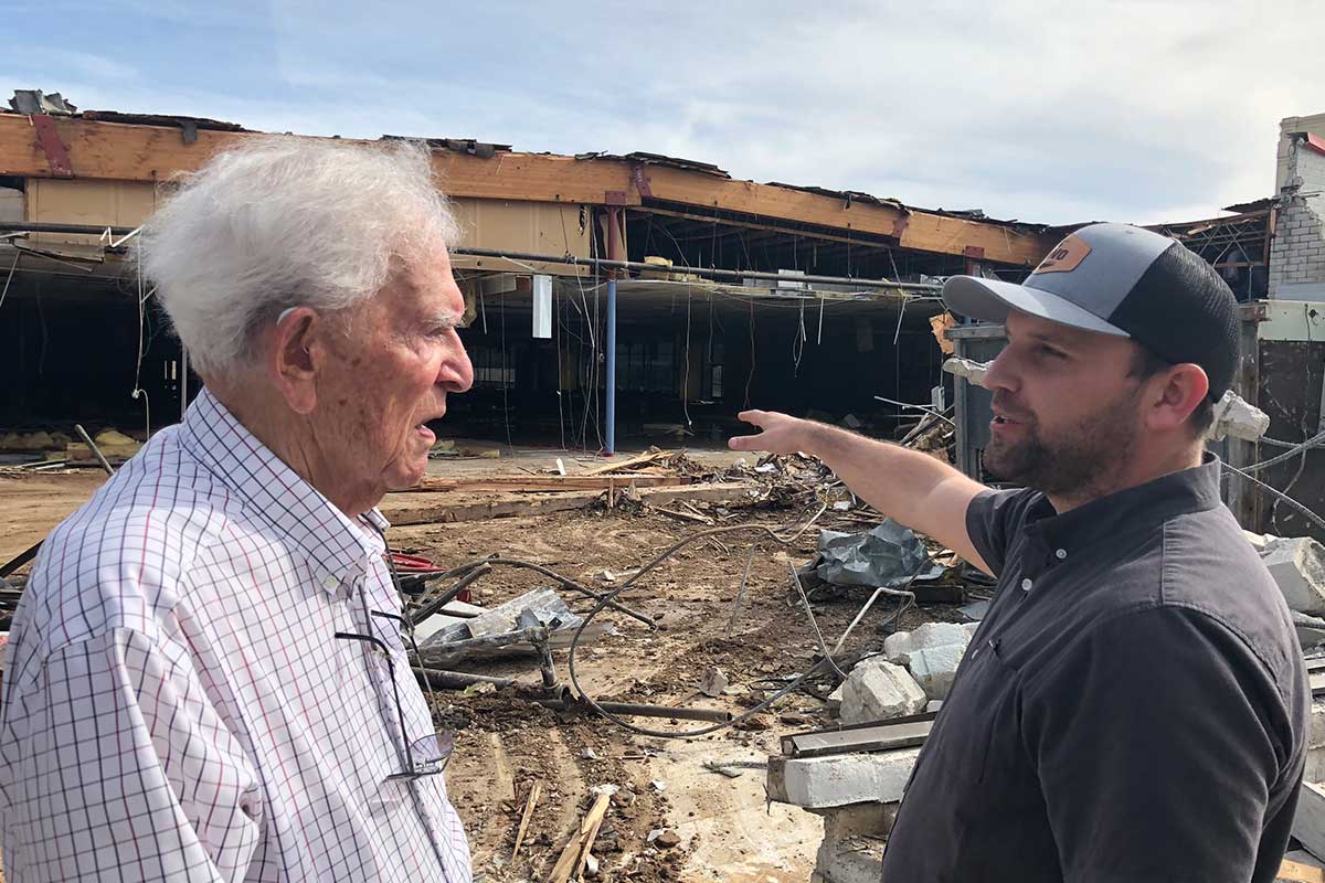 Photo of two men viewing demolition of an old building.
